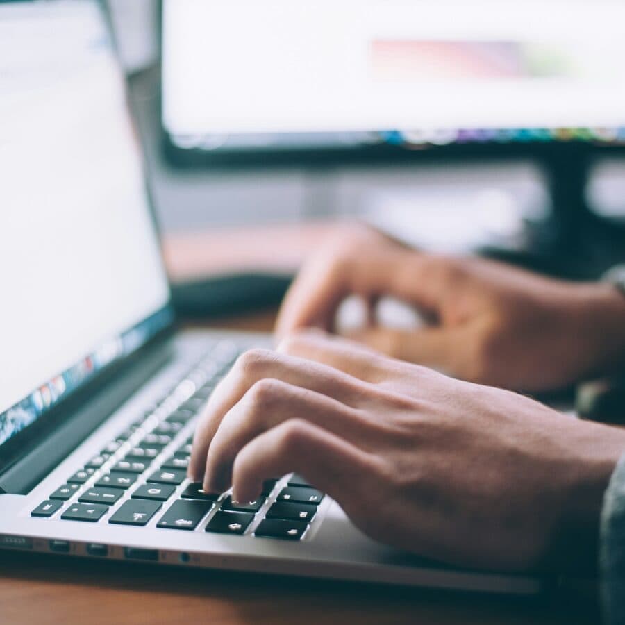 Hands typing on a laptop keyboard while learning to code